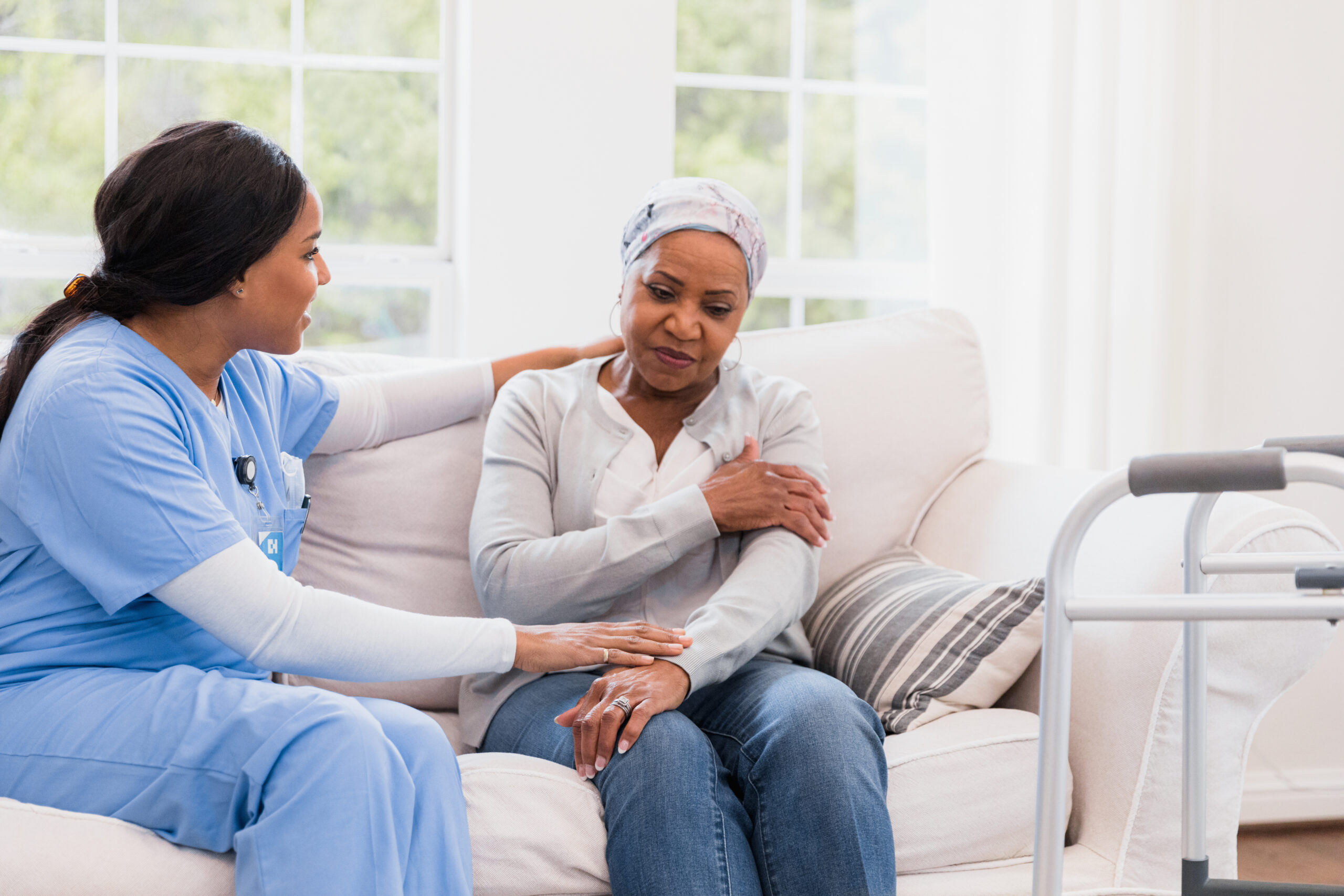 Female home healthcare nurse comforts depressed female cancer patient
