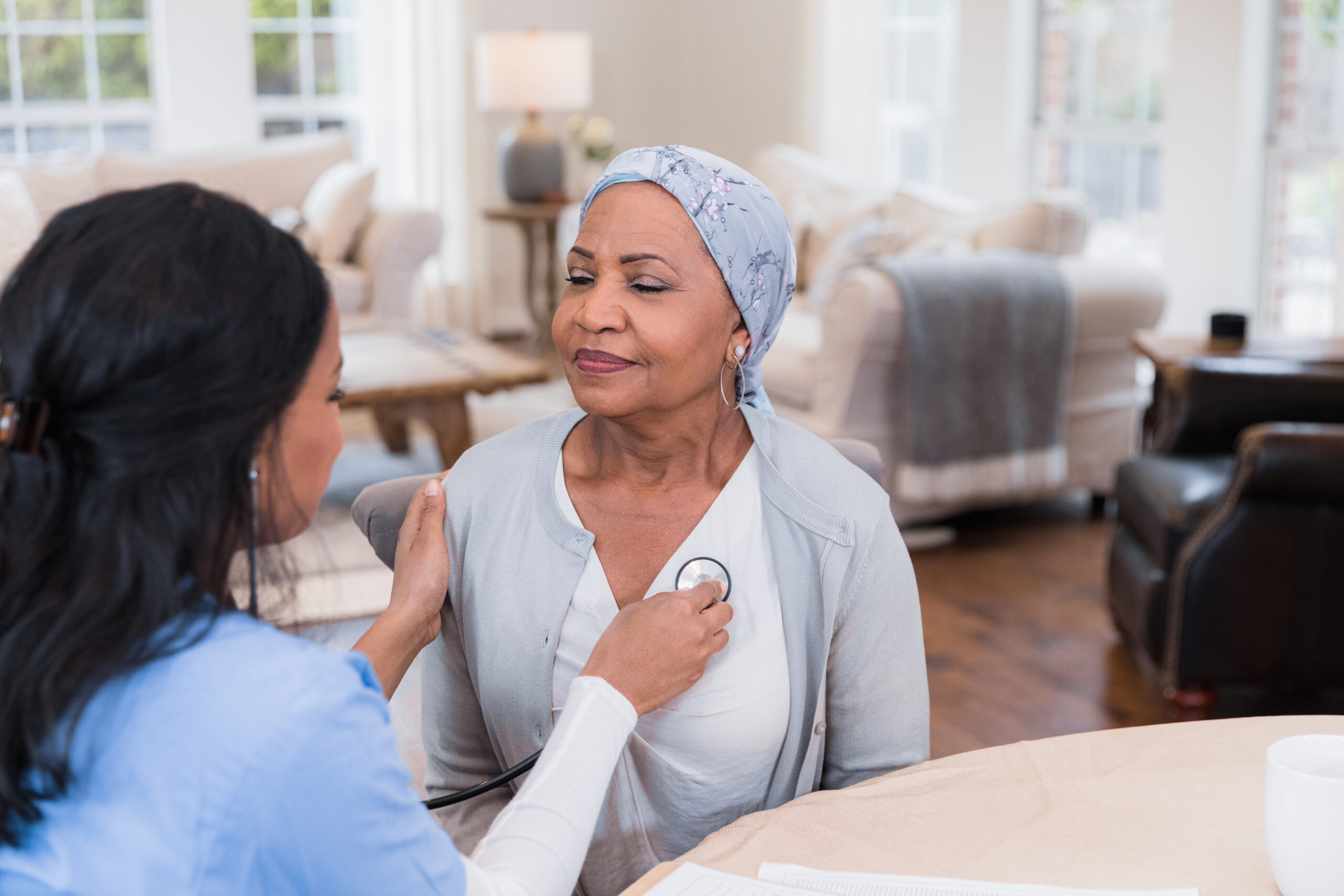 Cancer patient closes eyes as home healthcare nurse checks heart